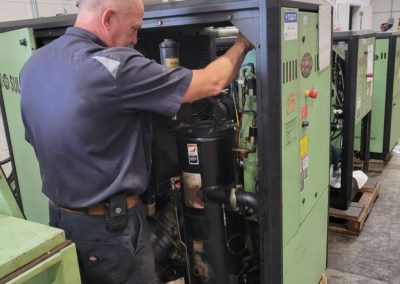 A technician working on a Sullair industrial air compressor