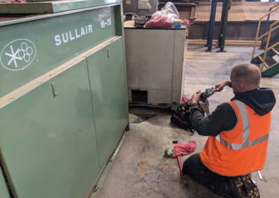 Technician servicing a Sullair industrial air compressor
