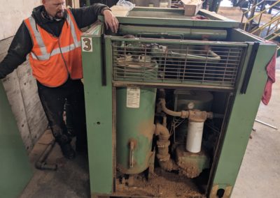 A technician servicing an industrial air compressor at a saw dust factory