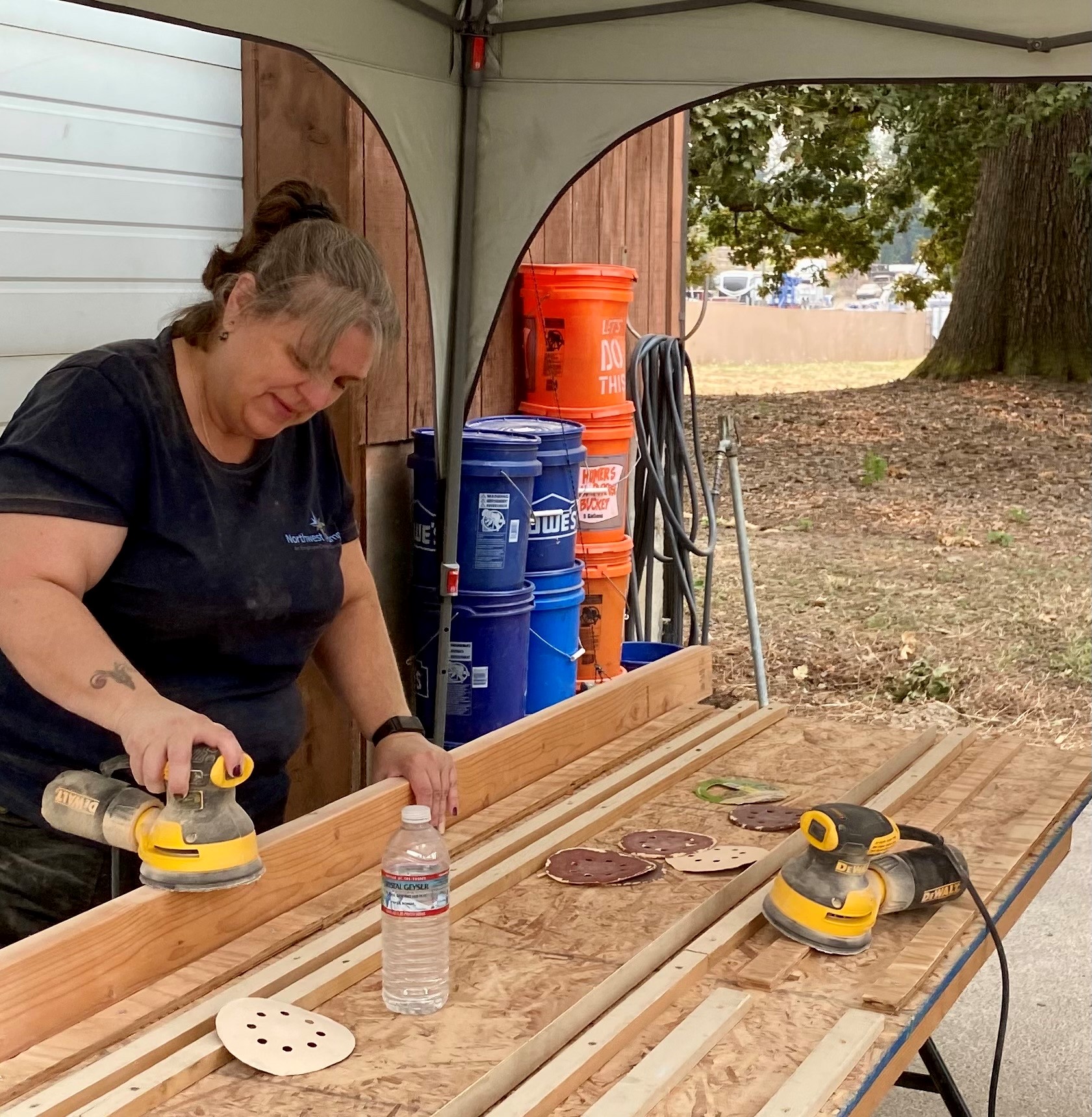 What an employee owned company looks like: a woman in Northwest Pump shirt doing carpentry work for a community outreach project.